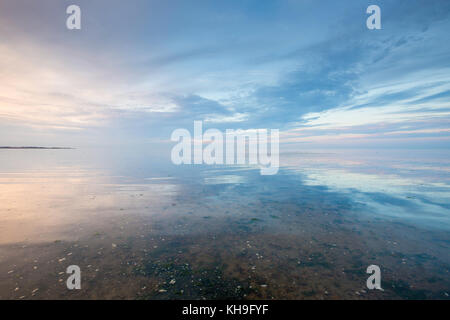 Cloud reflection in the shallow water at Seasalter beach, Whitstable, Kent, UK. The view is of the Swale Estuary and the Isle of Sheppey. Stock Photo