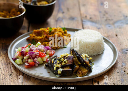 Indian meal with masoor dal - lentil curry, dahi baingan, rice and salad Stock Photo