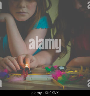 Girls playing with electronics kit light a lightbulb Stock Photo