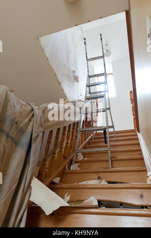 Dangerous tricky position decorating stripping on home stairs on a ladder needing risk assessment health and safety accident looming if careless Stock Photo