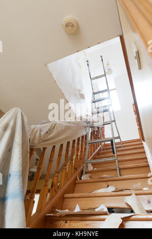 Dangerous tricky position decorating stripping on home stairs on a ladder needing risk assessment health and safety accident looming if careless Stock Photo