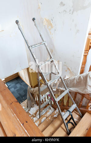 Dangerous tricky position decorating stripping on home stairs on a ladder needing risk assessment health and safety accident looming if careless Stock Photo