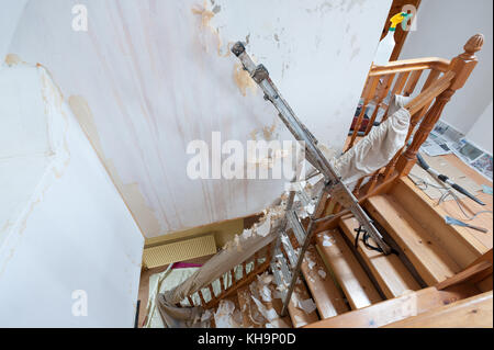 Dangerous tricky position decorating stripping on home stairs on a ladder needing risk assessment health and safety accident looming if careless Stock Photo