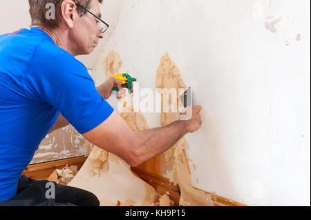 Dangerous tricky position decorating stripping on home stairs on a ladder needing risk assessment health and safety accident looming if careless Stock Photo