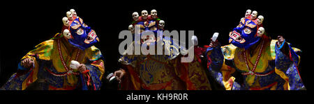 Three Tibetan monks are dancing the sacred dance of the mask: the lamas in the huge blue masks of Mahakala, decorated with white human skulls on top. Stock Photo