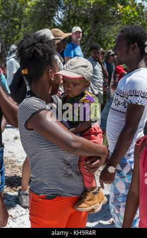 A young woman holding a baby at Zebu sacrifice ceremony, Lake Ampitabe, Toamasina, Madagascar, Africa Stock Photo