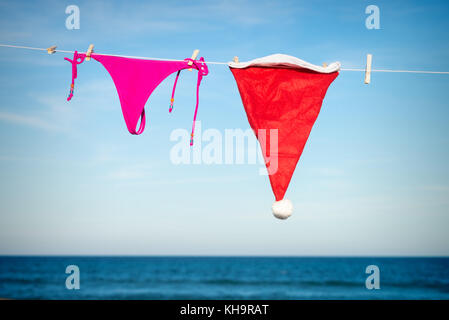Bikini tanga and Santa hat drying on a sunny beach, a seasonal getaway concept Stock Photo