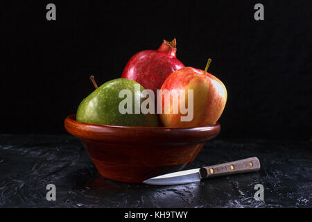 A fine art image of delicious looking pomegranate and apples in a bowl and a knife. Stock Photo