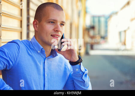 Outdoor portrait of modern young businessman talking with mobile phone in the city street. Close up. Copy space Stock Photo