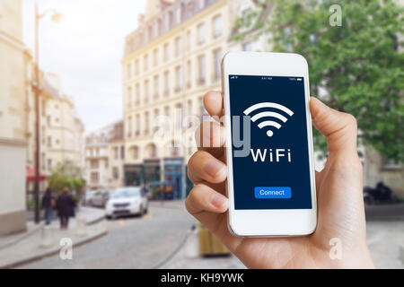 Connection to public WiFi hotspot in the city street to access internet on smartphone, concept about wireless technology and travel, close-up of hand Stock Photo