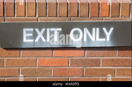 exit only sign affixed to a red brick wall. Stock Photo