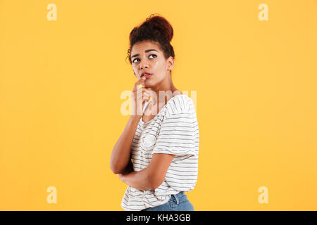 Pensive thoughtful african woman looking up isolated over yellow Stock Photo