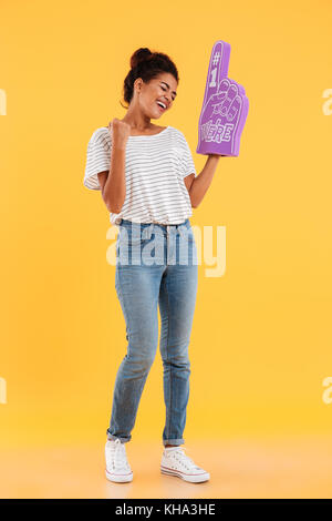 Happy african winner lady in casual clothes with fan finger standing and smiling isolated Stock Photo