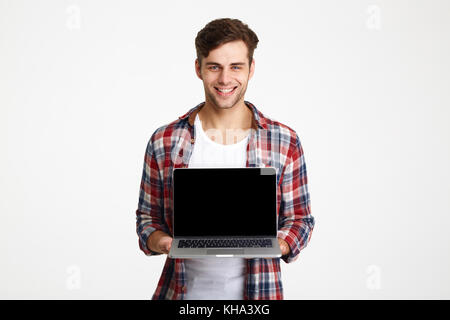 Portrait of a happy cheerful man showing blank screen laptop computer and looking at camera isolated over white background Stock Photo