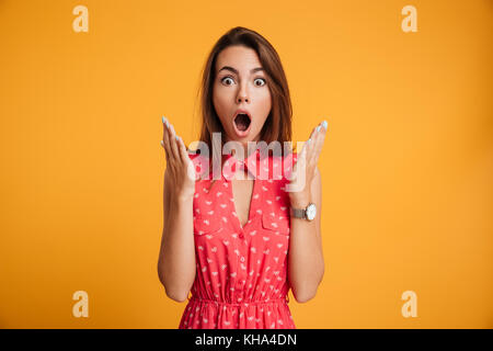 Photo of pretty shocked emotionally woman in red dress looking at camera with opened mouth Stock Photo