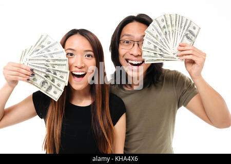 Close up portrait of a joyful satisfied asian couple showing bunch of money banknotes isolated over white background Stock Photo