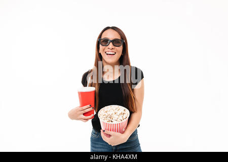 Portrait of a laughing asin girl in 3d glasses holding popcorn box and looking at camera isolated over white background Stock Photo