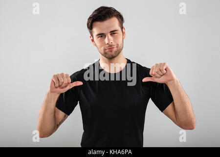 Image of handsome young sports man posing isolated over grey wall background. Looking camera pointing to himself. Stock Photo