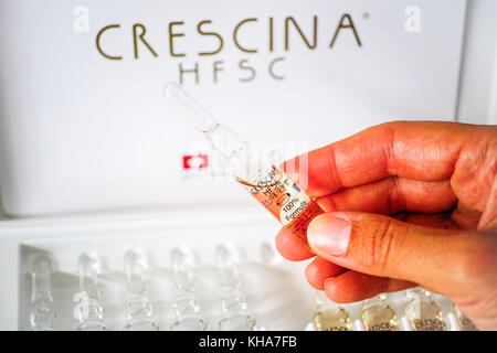 Paphos, Cyprus - November 13, 2015 Woman hand with ampoule of Crescina HFSC Re-Growth formula in front of Crescina treatment box. Crescina HFSC preser Stock Photo