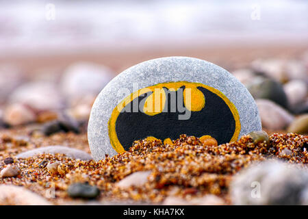 Paphos, Cyprus - November 22, 2016 Pebble with painted sign Batman on the beach with sand and stones. Closeup. Stock Photo
