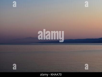 First light reveals Lefkada island in the distance as seen from Vouti beach, Kefalonia, Greece Stock Photo