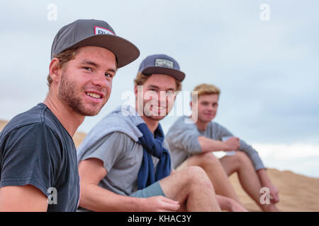 Young men sitting on a sand dune, Namibia Stock Photo
