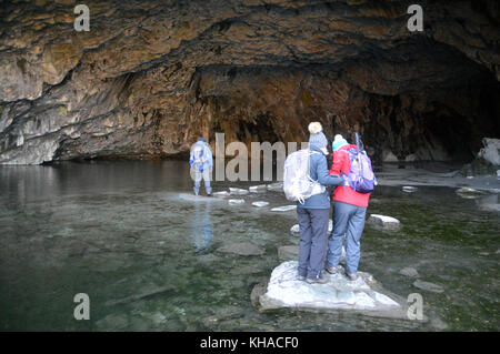 Three Fell Walkers Entering Rydal Cave on Stepping Stones above Rydal Water in the Lake District National Park, Cumbria, UK. Stock Photo
