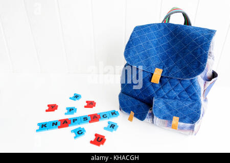 Blue bag with puzzle letters on white table. Hand made backpack. Stock Photo
