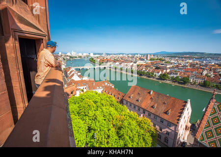 Young attractive man enjoying the view to old city center of Basel from Munster cathedral, Switzerland, Europe. Stock Photo