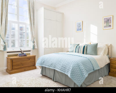 A fresh, light, traditional yet contemporary bedroom furnished with a king sized bed, chest & fitted wardrobe Stock Photo