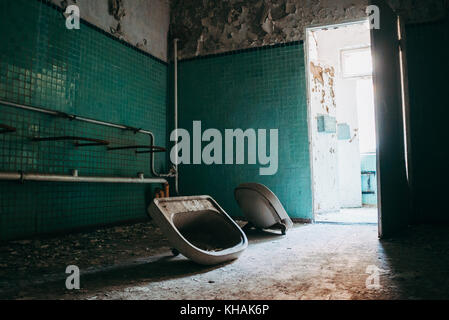 Two hand basins lie detached from the wall inside an abandoned building in Chernobyl, Ukraine Stock Photo