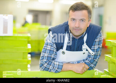 Portrait of male worker leaning on plastic crate Stock Photo