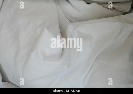 White delicate soft background of fabric or bedding sheet in dark room, background. Stock Photo