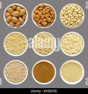 Almonds in white bowls over gray. Whole nuts with shells, shelled, blanched, chopped, slivered, sliced, ground, brown and white almond butter. Photo. Stock Photo