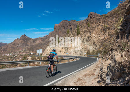 Cyclist person cycling on a road bike with mountain views inland just beyond Cruz Grande on the GC-60 road, Gran Canaria, Canary Islands, Spain Stock Photo