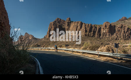 Cyclist cycling a hairpin bend on a road bike with mountain views inland descending to Cruz Grande on the GC-60 road, Gran Canaria Stock Photo