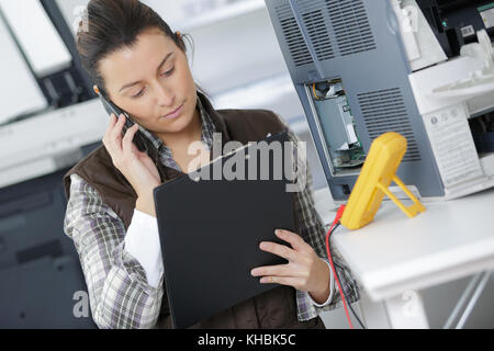 female technician with a clipboard talking on the phone Stock Photo