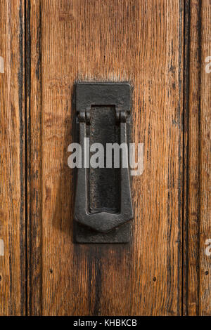 A substantial black cast iron, combined door knocker & letterbox fitted to an aged, tongue & groove oak front door. Stock Photo