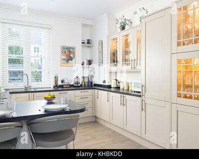 A fresh, light, traditional yet contemporary kitchen. furnished with fitted cabinets & a breakfast bar Stock Photo