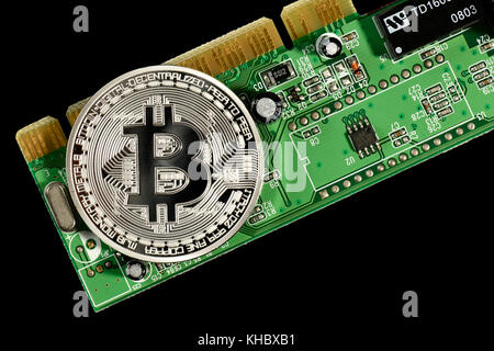 Symbol image digital currency, silver physical coin Bitcoin on printed circuit board Stock Photo