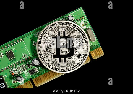 Symbol image digital currency, silver physical coin Bitcoin on printed circuit board Stock Photo