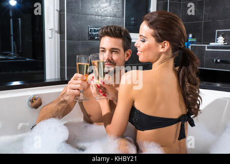 Beautiful young couple relaxing together and drinking Champagne in the Whirlpool. Stock Photo
