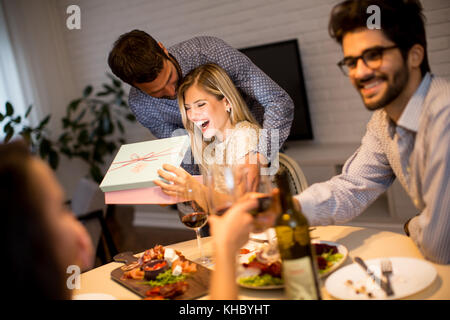 Happy smiling young woman receives gift from young man for New Year or Christmas at home Stock Photo