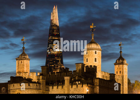 London's old and new architecture with the Shard skyscraper towering behind the floodlit Tower of London at dusk. Stock Photo
