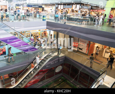 ROTTERDAM, HOLLAND - AUGUST 24, 2017; Escalator well with escalators down several floors , shops and people some blurred in movement in modern retail  Stock Photo