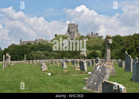 A view of the ruins of  the National Trusts Corfe Castle standing on a hill taken from the cemetary with gravestones in the foreground. Stock Photo