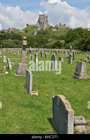 A view of the ruins of  the National Trusts Corfe Castle standing on a hill taken from the cemetary with gravestones in the foreground. Stock Photo