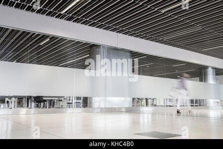 Blurred image of woman walking through modern airport terminal building Stock Photo