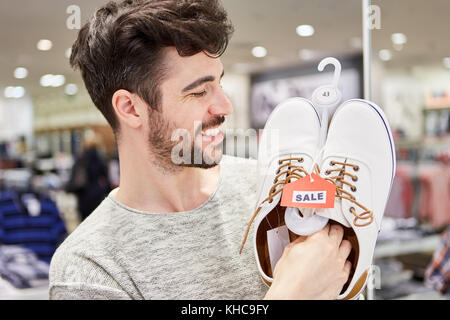 Young man shopping enjoys shoes in fashion store Stock Photo