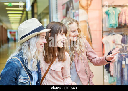 Group of friends admire fashion shop window during shopping Stock Photo